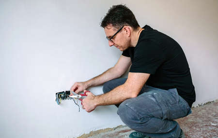 Male electrician cutting cables to the electrical installation of a house