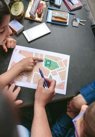 Top view of mother explaining to her children the assembly point map while preparing emergency...