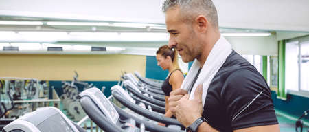 Portrait of smiling man training over a treadmill in the gym