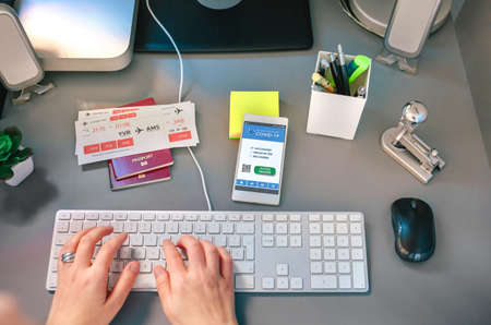 Unrecognizable woman booking trip online from home looking at covid health passport in the mobileの写真素材