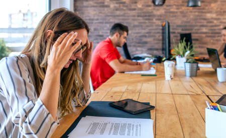 Stressed businesswoman with hands on head looking at documentsの写真素材