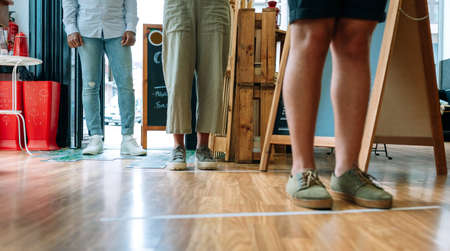 Unrecognizable people queuing up keeping social distance to enter a shopの写真素材