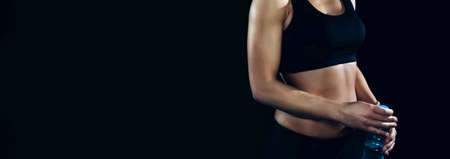 Portrait of unrecognizable sportswoman with black top posing over a dark backgroundの写真素材
