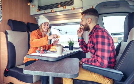 Happy friends having breakfast in a camper van in the morning