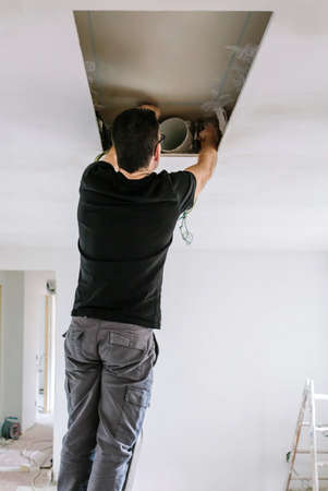 Unrecognizable man preparing extractor hood installation on kitchen ceilingの写真素材