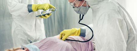Doctors in a field hospital examining and auscultating coronavirus patientの写真素材