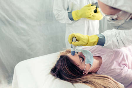 Unrecognizable doctors in a field hospital taking the fever a patient