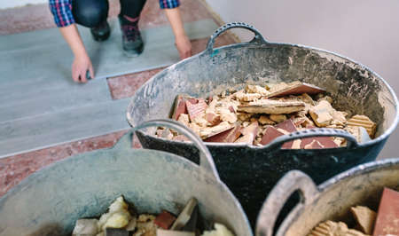 Construction rubble buckets with unrecognizable female bricklayer working in the background. Selective focus on buckets in foregroundの写真素材