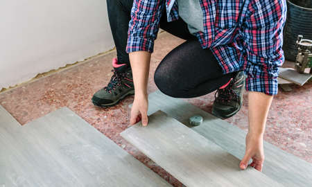 Unrecognizable crouched female bricklayer placing tiles to install a floorの写真素材