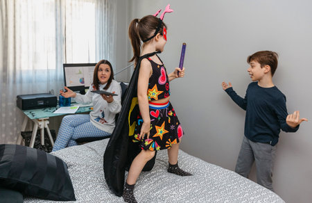 Children playing bothering their mother who is teleworking at home. Conciliation family work conceptの写真素材