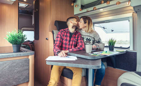 Couple kissing while telecommuting during a camper van trip