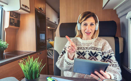 Woman talking looking at camera on videoconference from her camper vanの写真素材