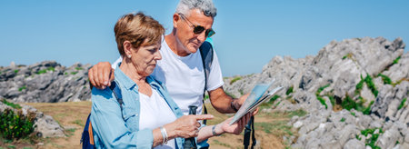 Senior couple with poles hiking looking map outdoorsの写真素材