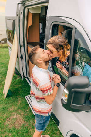 Young couple kissing through the camper van window during a trip