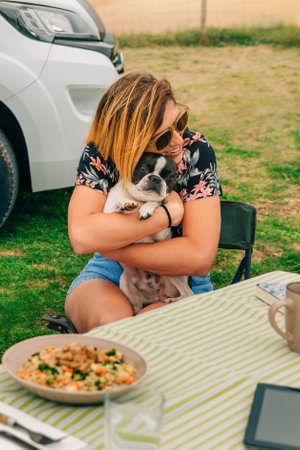 Portrait of happy young woman hugging lovely dog sitting outdoorsの写真素材