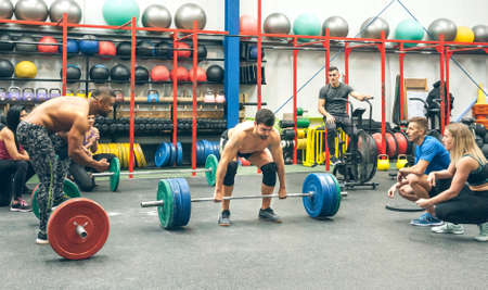 Strong man practicing weightlifting in the gym with his partners cheering him onの写真素材