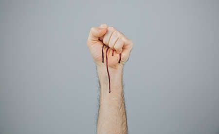 Conceptual bleeding clenched fist over gray backgroundの写真素材