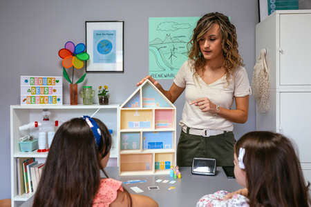 Teacher in an ecology classroom explaining to her students the parts of a sustainable houseの写真素材
