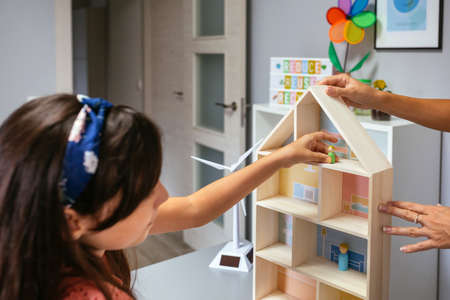 Female student in an ecology classroom placing dolls in a houseの写真素材