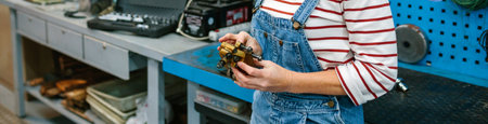Unrecognizable mechanic woman checking caliper brake system in front of workbench on factory