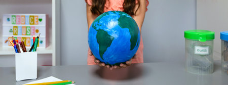Unrecognizable female student holding in her hands a handmade globe world at ecology classroom. Sustainable lifestyle education concept.の写真素材