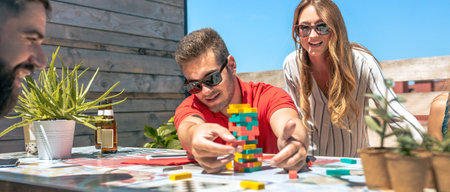 Concentrated young man with sunglasses catching game piece next to his happy office colleagues on terrace in a coffee breakの写真素材