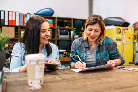 Cheerful females entrepreneur working in a small business to sell through online ecommerce. Women partners checking stock and orders in vintage shop.の写真素材