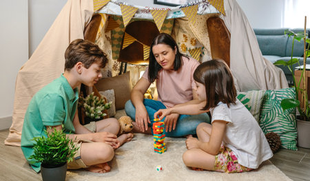 Happy mother and sons having fun while playing together with wooden stacking piece game in front of...