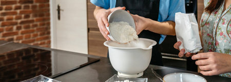 Banner of unrecognizable teenage boy wearing an apron pours flour into a mixing bowl while baking...