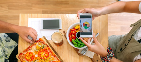 Top view of unrecognizable young girl taking video of fresh poke bowl salad with smartphone in a restaurant. Culinary blogger creating content for social media about healthy lifestyle and vegan food.の写真素材