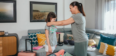 Banner of mother and daughter joyfully preparing clothes and packing a suitcase for summer vacation, trying on bikinis and sharing smiles, embodying the excitement of travel and holiday adventuresの写真素材