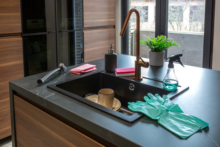 Cleaning products and equipment are neatly arranged near a modern kitchen sink, showcasing a clean and organized space ready for dishwashing or other kitchen tasksの写真素材