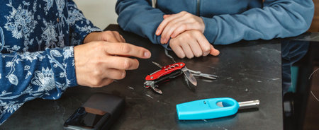 Banner of mother hand pointing at multi tool knife while explaining emergency kit to teenage daughter with lighter and battery charger. Alert, foresight and self sufficiency family strategy.の写真素材