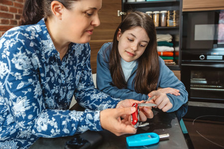 Smiling mother showing her daughter how to use a multi tool knife of 72 hours emergency kit. Family preparing alert, foresight and self sufficiency strategy. Survival food pantry stored in cupboard.の写真素材
