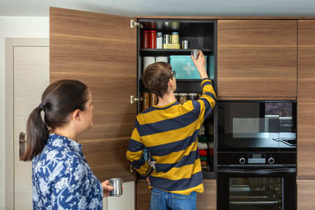 Unrecognizable family preparing for potential emergencies or food scarcity. 72 hours survival kit. Mother and son organizing food supplies, storing canned goods and non perishable items in pantry.の写真素材
