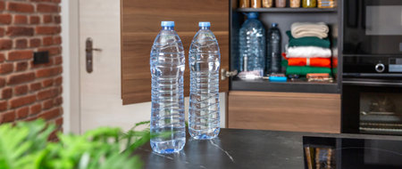 Banner of two water bottles placed on kitchen counter, in front of pantry with 72 hours survival kit. Alert, foresight and self sufficiency strategy. Emergency food and supplies stored for disasters.の写真素材