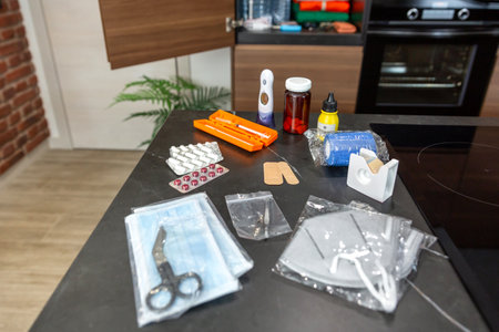 Medical supplies on kitchen table, including daily medication, medicines, insulin injection, pills, bandages and disinfectant. First aid kit prepared according to government emergency recommendations.の写真素材