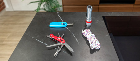 Banner of 72 hour survival kit on kitchen counter including flashlight, rope, multitool knife and...