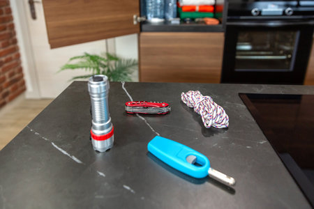 Emergency kit on kitchen counter with multitool knife, lighter, flashlight and rope ensuring safety...