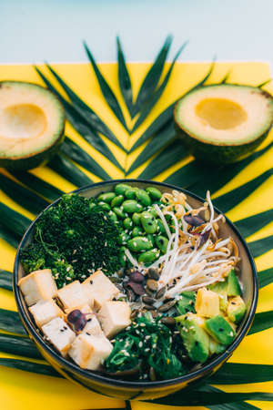 vegetarian dish. Poke bowl with tofu. top view on white and yellow backgroundの写真素材