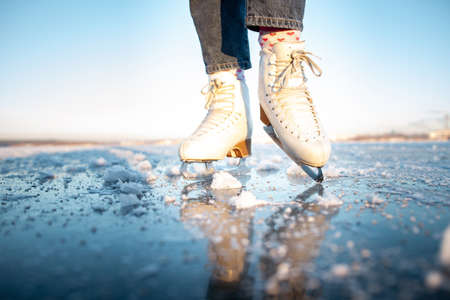 Close-up of a woman's legs in white ice skates on the frozen lakeの写真素材