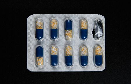 pills in pack on black background Yellow blue white