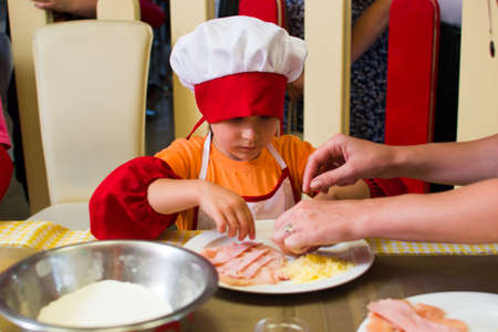 Alchevsk, Ukraine - July 23, 2017: School cook for children. Meat rolls with cheese are prepared.のeditorial素材