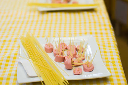 Raw pasta and sausage on a white plate.の写真素材