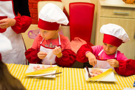 Alchevsk, Ukraine - July 30, 2017: School cooks for children. Learn to cook pasta with sausages -のeditorial素材