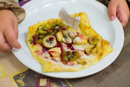 children prepare fruit pizza at the tableの写真素材