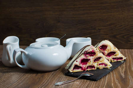 a teapot and a couple of cups with a cake on the table.の写真素材