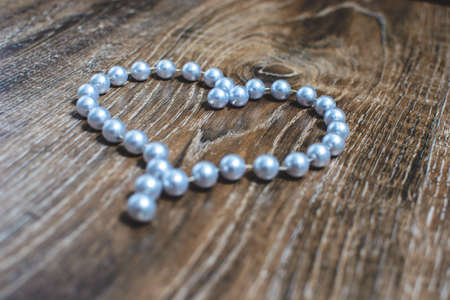 heart made of beads on a wooden background.の写真素材