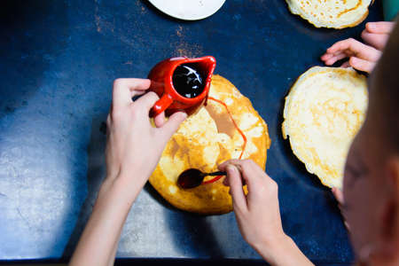 children stuff and decorate pancakes with jam and powder their own hands.の写真素材
