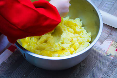 stirring dough in an iron bowl with a spoon.の写真素材